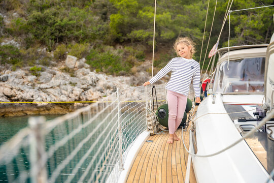 Young girl enjoying sea breeze on deck of sailing yacht in Croatia. Peaceful moment at sea represents childhood freedom, relaxation and connection with nature