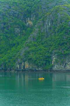 Tourists kayaking through an oyster pearl farm and lush green limestone mountain in Ha Long Bay, Vietnam