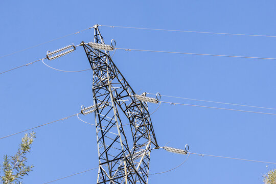 Electricity pylon distributing high voltage power lines against blue sky