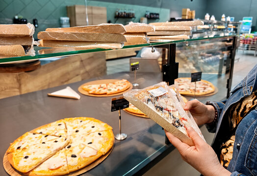 Counter in a supermarket selling ready-made pizza, where customers choose a pre-packaged slice of pizza.