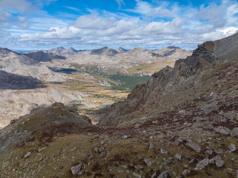 Aerial view of Mount Harvard and the surrounding rocky alpine landscape with sparse vegetation and scattered boulders under a blue sky with clouds in Buena Vista, Colorado, United States.