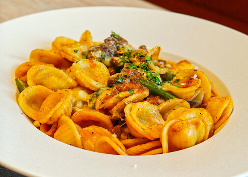 Orecchiette pasta (shaped like little ears) with a tomato-based sauce, meat (similar to sausages or a ragout), herbs and green beans or cabbage.