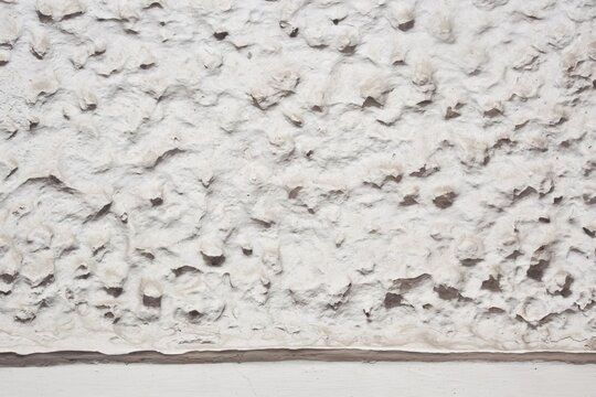 Biała ściana o oryginalnym tynku strukturalnym. A white wall with a distinctive textured plaster finish.	