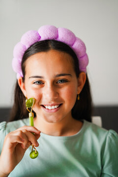 Female influencer kid wearing headband while using quarz roller for beauty care - Cosmetic and child concept - Focus on eyes - Vertical UGC photo