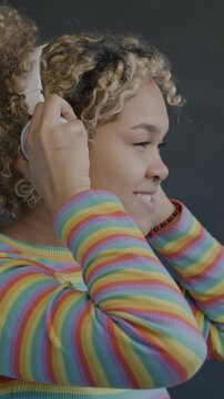 Side view of African American woman putting on headphones dancing on black background. Music and entertainment concept.