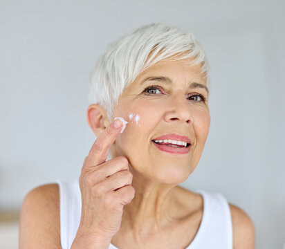 Beauty portrait of a sensual senior mature woman applying moistirizing cream on her face, skin care and fashion concept. Aesthetic cosmetology and dermatology, face care and facial treatment concept