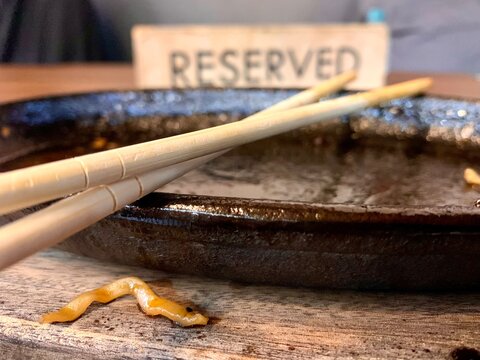 Extreme close up of chopsticks on empty dirty sizzler plate with reserved sign background