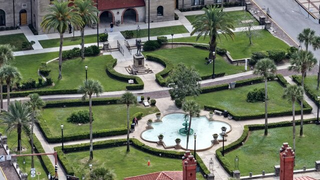 Aerial view of the Lightner Museum courtyard featuring a central fountain, manicured hedges, palm trees, and a statue in St. Augustine, Florida, United States.