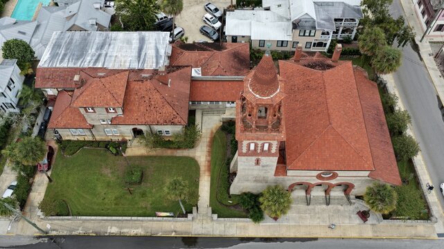 Aerial view of Grace United Methodist Church featuring its distinctive terracotta roof and bell tower, surrounded by lush green lawns and palm trees in St. Augustine, Florida, United States.