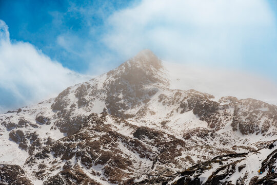 Snow-covered Cayambe volcano peak beneath drifting clouds