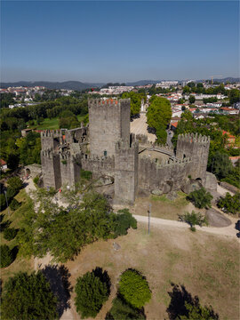 Aerial view of Guimaraes Castle with its stone walls and towers, surrounded by lush green trees and the historic cityscape of Guimaraes, Braga, Portugal.