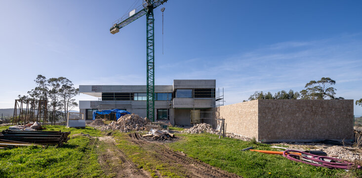 Modern house construction site with tower crane and debris