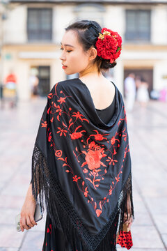 Woman in floral flamenco dress with red flower hairpiece