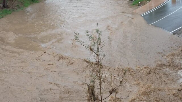 Overflowing river flash flood submerging a road