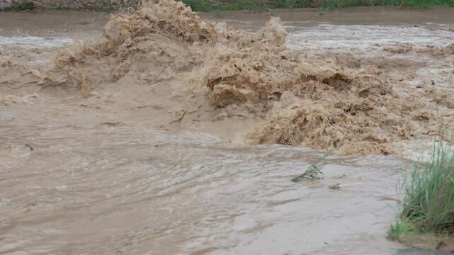Raging muddy river overflowing during flash flood