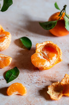 Fresh tangerines with peeled segments and green leaves