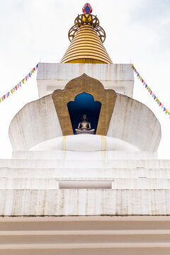 Buddhist stupa with meditation statue and prayer flags