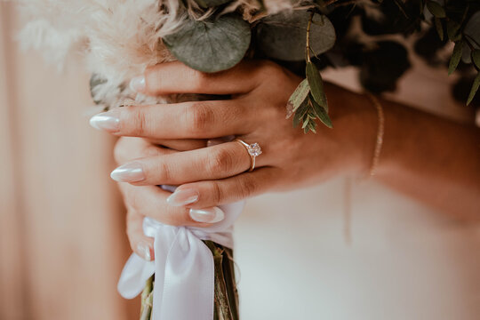 Bride holding bouquet with engagement ring and silk ribbon
