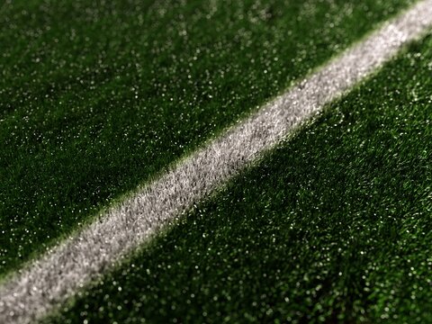 White line on green grass soccer field close-up