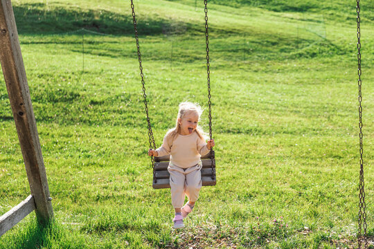 Young girl on swing in sunny green lawn