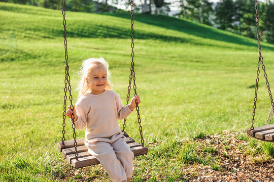 Young girl on swing in sunny green park