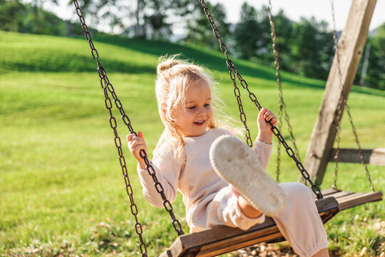 Girl play on swing over sunny green lawn