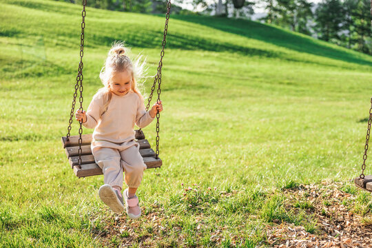 Little girl on a swing in a sunny green park