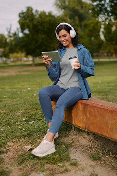 Woman drinking coffee while using tablet outdoors