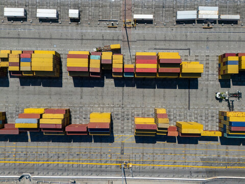 Aerial view of the Port of Long Beach featuring rows of colorful shipping containers stacked on the terminal ground in Long Beach, California, United States.