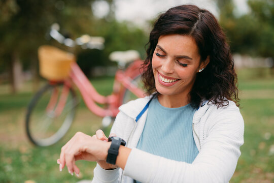Woman checking fitness smartwatch after cycling in park