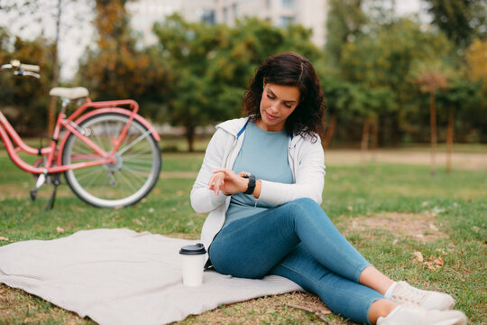 Woman checking smartwatch data relaxing in park