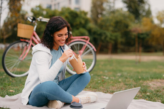 Woman eating while working remotely in park