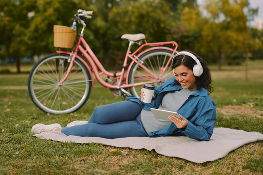 Woman relaxing in park enjoying digital content outdoors