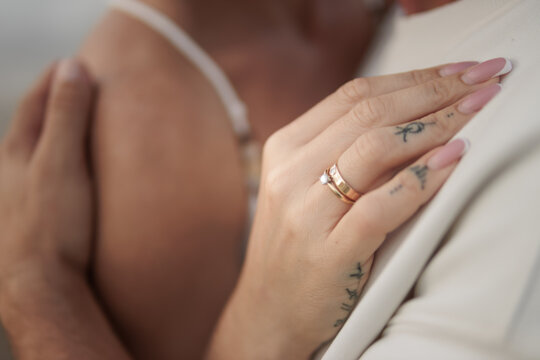 Woman's hand with engagement ring and wedding band embracing a partner, symbolizing love, commitment, and eternal union in a romantic moment