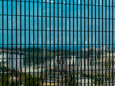 Aerial view of the glass facade of a modern office building reflecting the surrounding urban landscape and greenery in Katowice, Silesian Voivodeship, Poland.