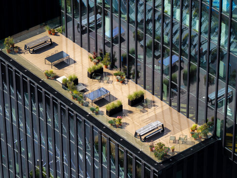 Aerial view of a modern office building terrace with wooden decking, outdoor tables, and potted plants in Katowice, Silesian Voivodeship, Poland.