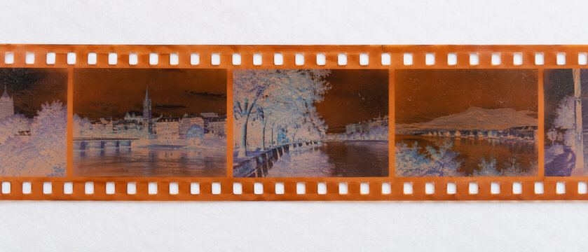 Orange 35mm color negative film strip with inverted scenes on white paper