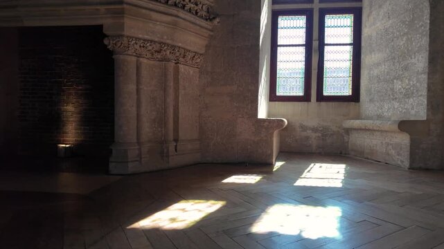Interior hall at Ch&acirc;teau de Pierrefonds featuring carved stonework, stained glass windows, parquet flooring and colorful light patterns