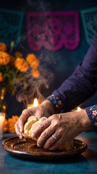 Skilled elderly hands breaking sweet bread beneath incense smoke for Dia de Muertos