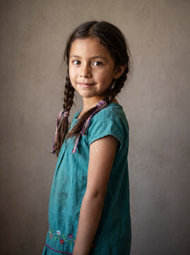 Poised young girl portrait in embroidered teal dress with braids, Day of the Dead