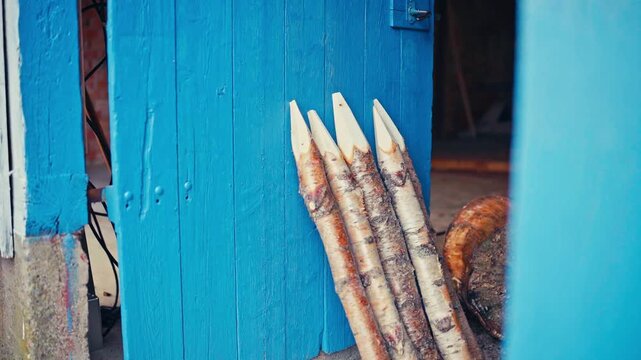 Sharpened Wooden Fence Stakes Lean Against A Blue Door Outside A Workshop On A Rural Farmstead In Norway. - timelapse shot