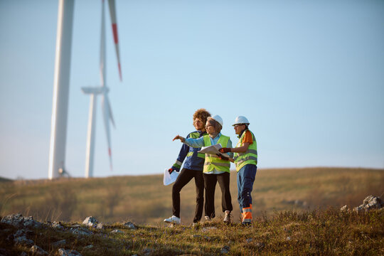 Engineers Inspecting Wind Turbines on a Wind Farm Field Discussing Renewable Energy Project Plans