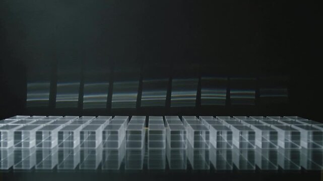 Tipping transparent blocks from edges, leaning inward on glass forming arch then settling upright