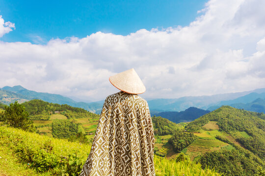 A woman admires the breathtaking scenery of rice terraces. Mu Cang Chai rice terraces on the mountain slopes.