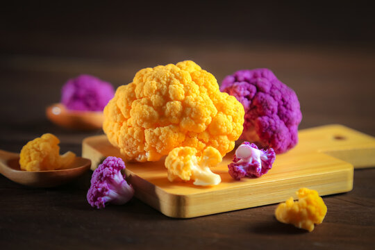 Multicolored cauliflower on a wooden table. Purple and yellow florets.