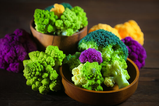 Multicolored cauliflower on a wooden table. Purple, yellow, and green florets. Rustic still life.