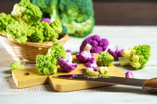 Multicolored cauliflower on a wooden table. Green and purple florets.