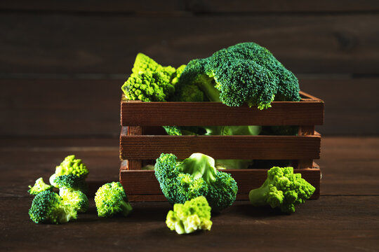 Broccoli and Romanesco cauliflower in a wooden crate on a table.