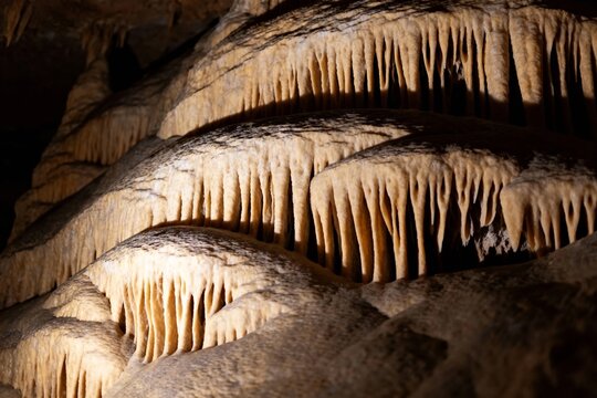 Stalactites and stalagmites formations in a limestone cave illuminated by artificial lighting