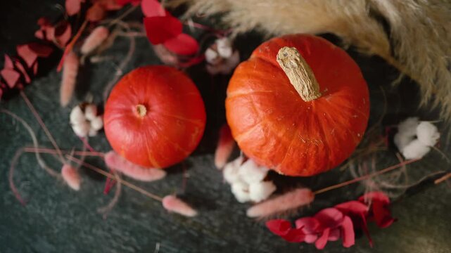 Bright orange pumpkin surrounded by autumn decorations, cotton, foliage, and rustic elements, creating a warm Halloween and fall atmosphere for seasonal, festive, and holiday content